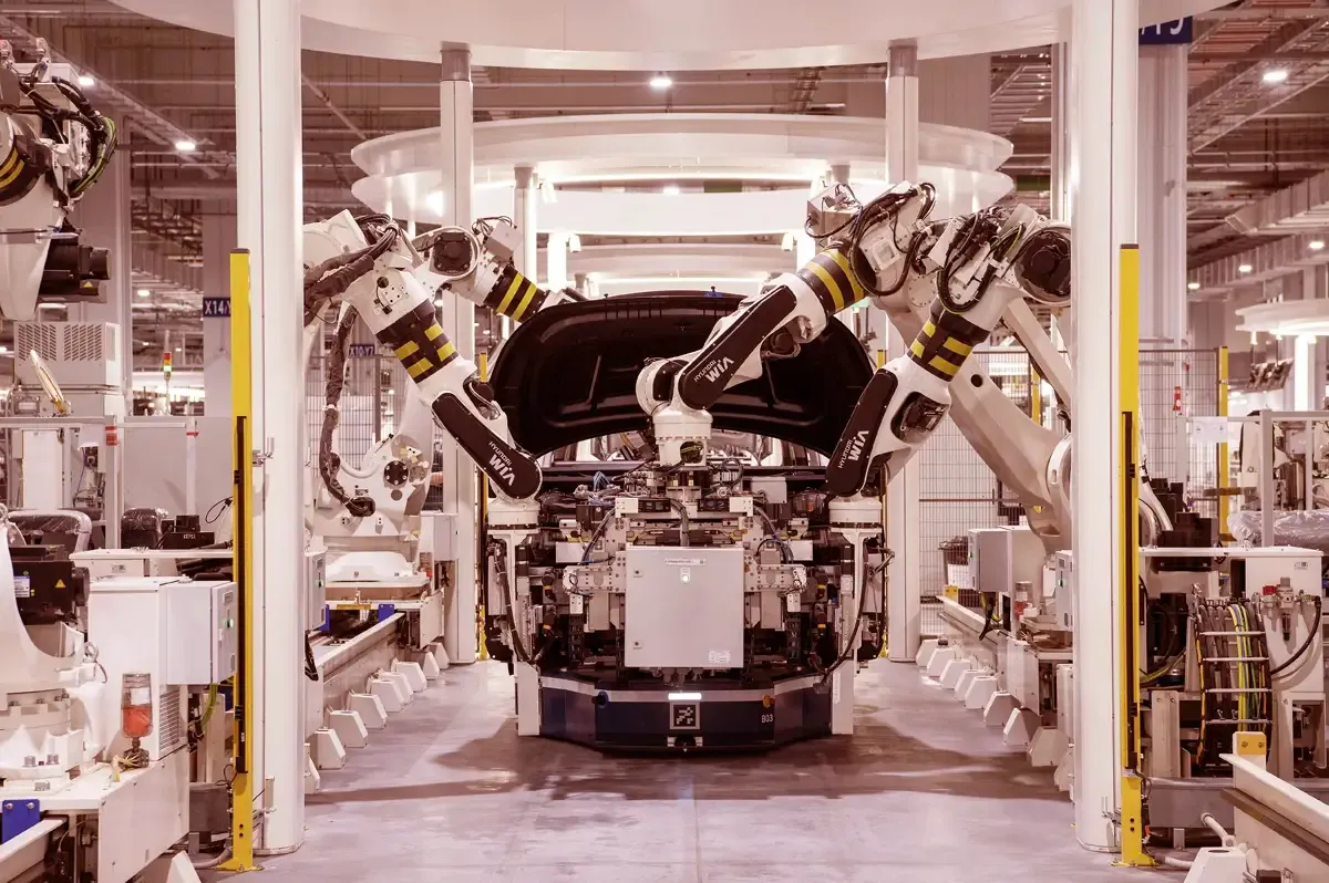Bras robotisés assemblant une pièce de carrosserie sur une ligne de production automobile